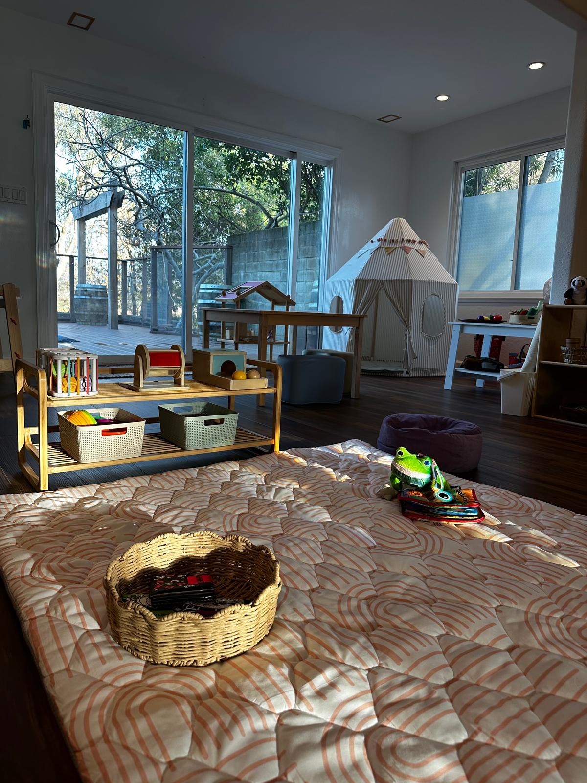 Sunlit playroom at Seed To Bloom with play tent and Montessori shelves